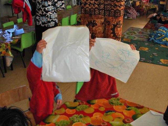 2 children each holding up a piece of paper with scribbles