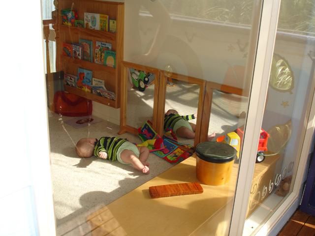 Baby lying on the floor surrounded by toys and books