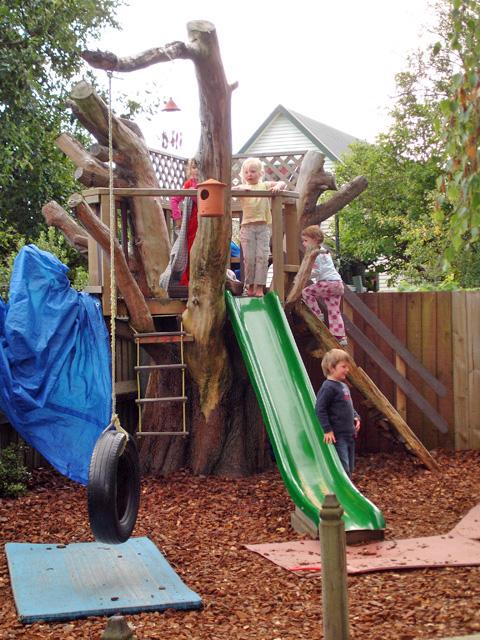 4 kids in the playground with a swing and slide