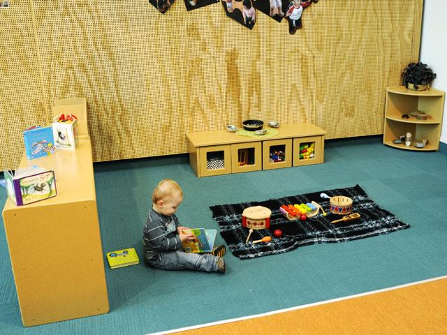 Boy playing on soft flooring with accessible play equipment