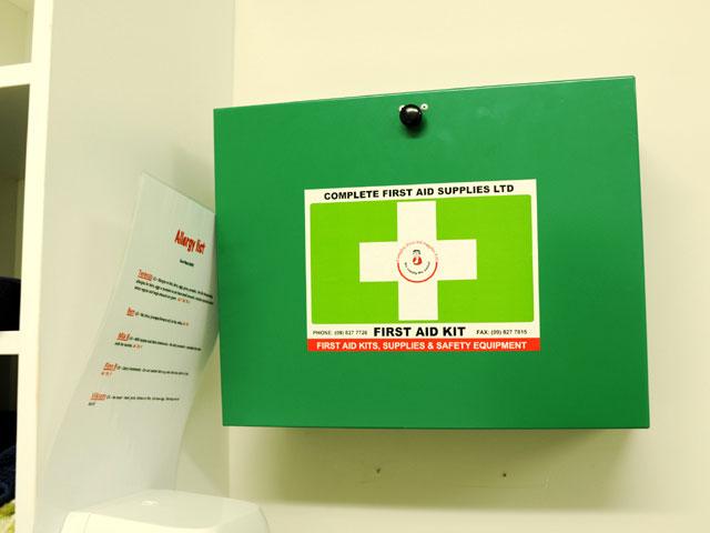 Green first aid kit with a white cross mounted on a wall