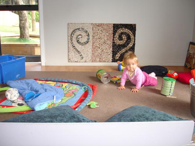 Baby on the floor with Māori symbols in the background